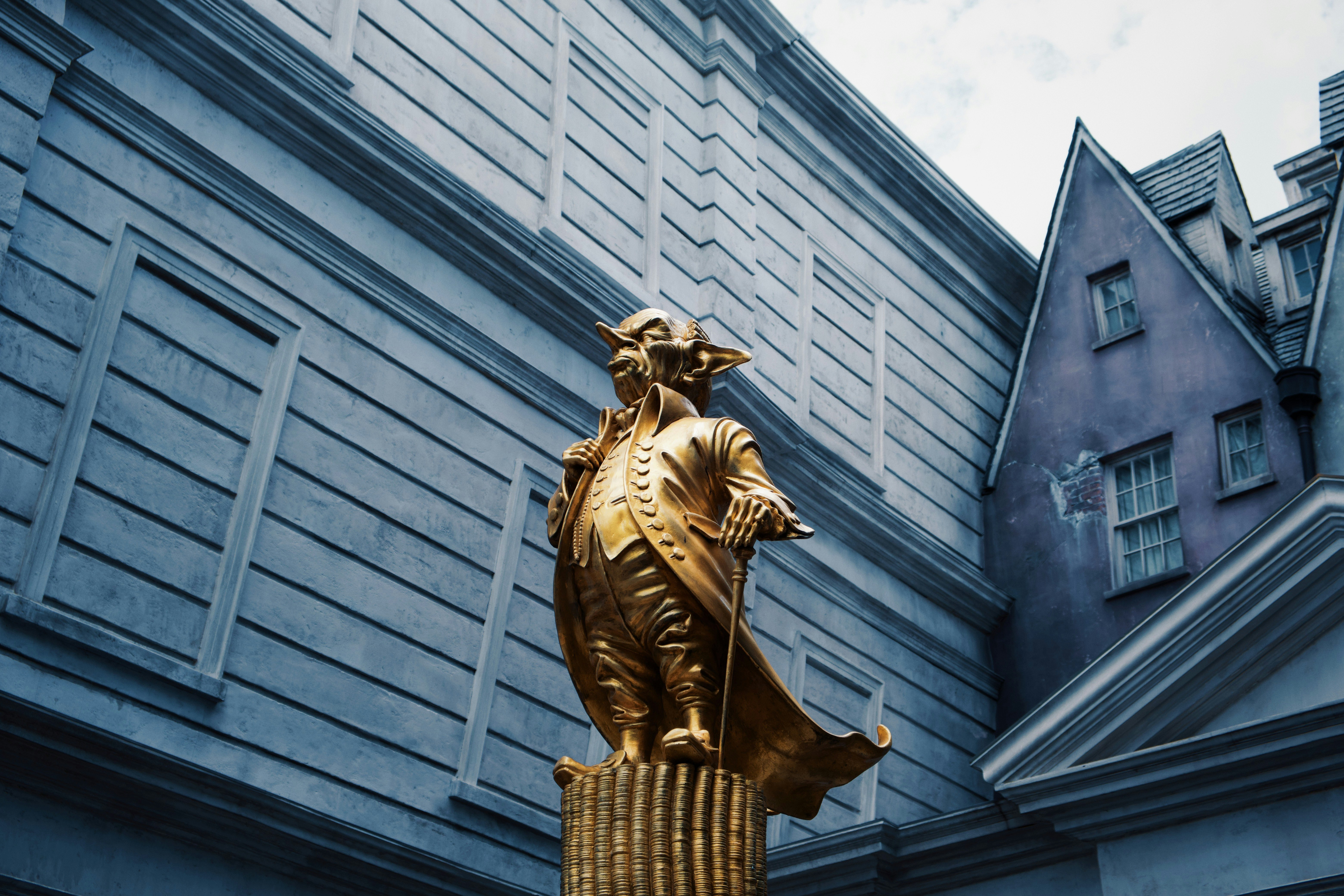 gold statue of man in front of gray concrete building